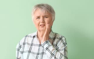 senior adult woman holding her jaw in pain